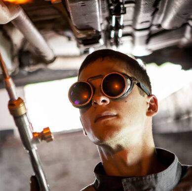 Mechanic inspecting a damaged car frame to highlight the importance of having short term insurance and specialised business insurance for vehicle repairs and risk protection.